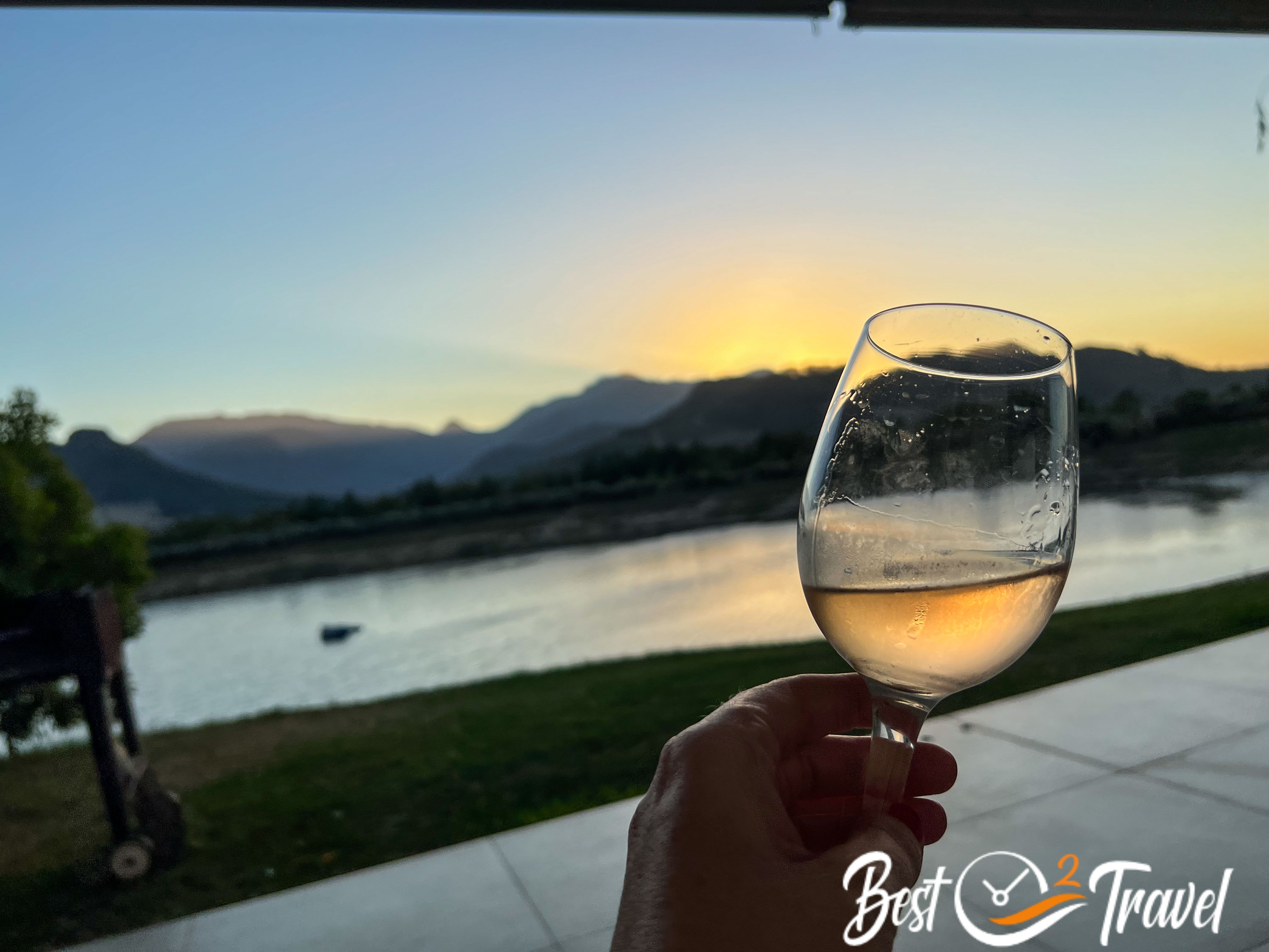 A half full wine glass in a beautiful landscape at sunset.
