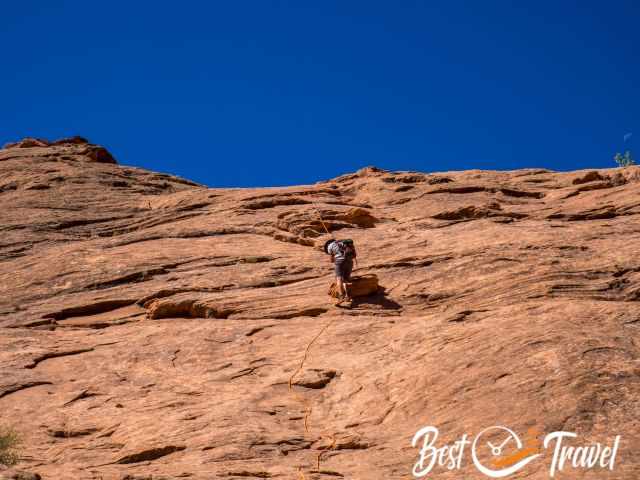 A hiker rapells down a slickrock wall