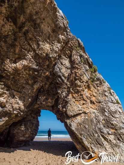 A visitor walking through the arch at Adraga Beach