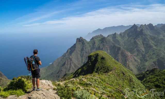 A hiker is looking to the rugged wild Anaga coastline on a sunny day