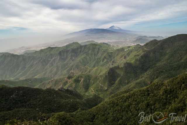 Anaga mountains near Taborno with deep green ridges and a snow‑covered Mount Teide in the background.