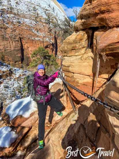 Female hiker with winter gear holding to a chain at Angels Landing.