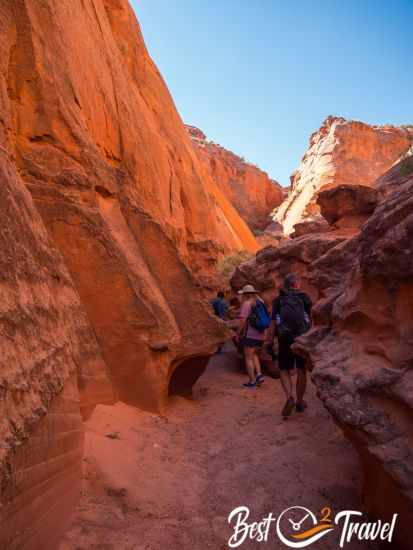 Visitors on the sandy path along a high canyon wall.