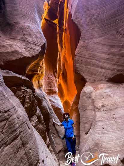 I in a narrow slot canyon with orange light in the back.