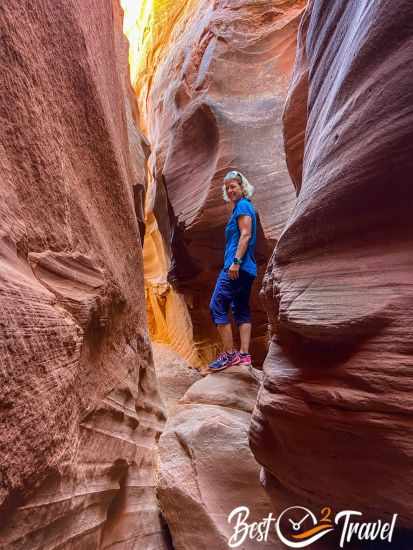 A hiker on a huge rock in a slot canyon.