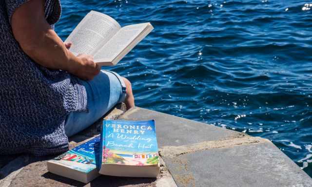 A woman reading a book at the sea