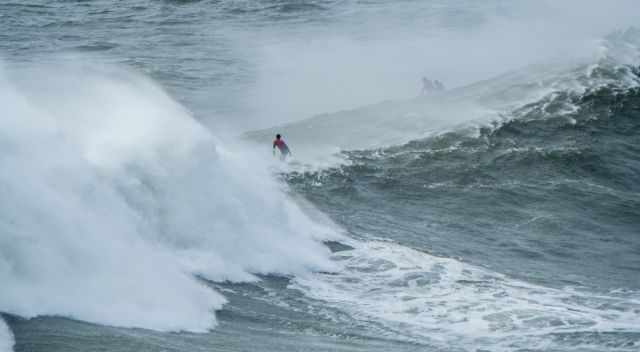 A monster wave behind a surfer in Nazare.