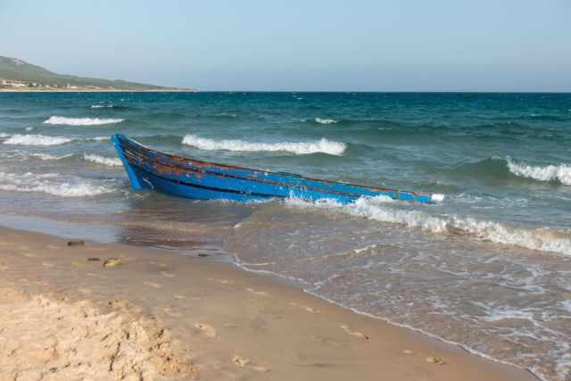 A colourful fisherboat almost flooded during high tide.