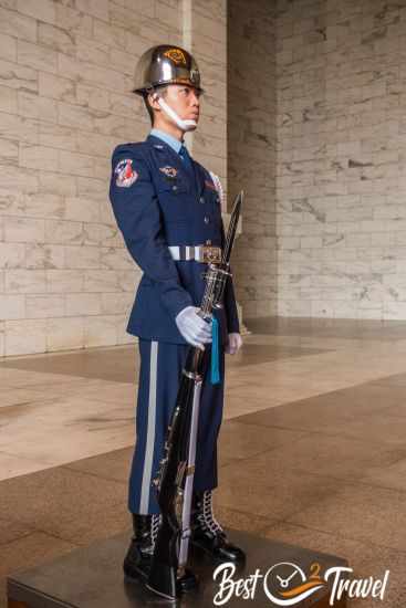A guard with his riffle stands motionless on the platform