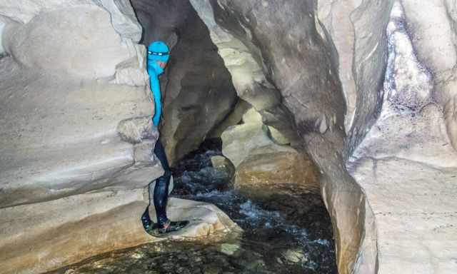 A man standing in the cave on a rock watching the Broken River
