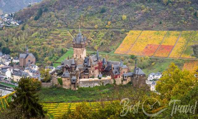 Cochem Castle from higher elevation with grapevines fall foliage also in red in the back
