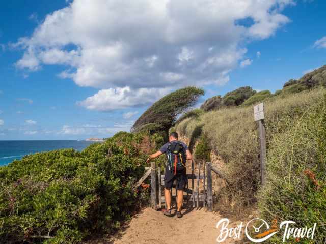 A hiker opens a gate to access the hiking path.