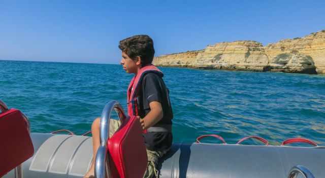 A boy sitting on the outer rip during the boat tour.