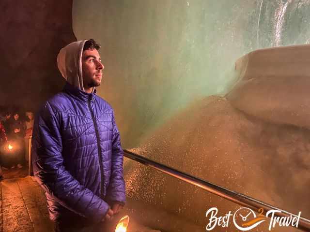 A visitor with warm winter clothes next to a ice wall.