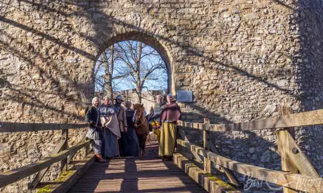 People in mediäval clothes in front of the archway