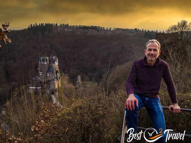 A visitor in front of Eltz Castle at sunset.