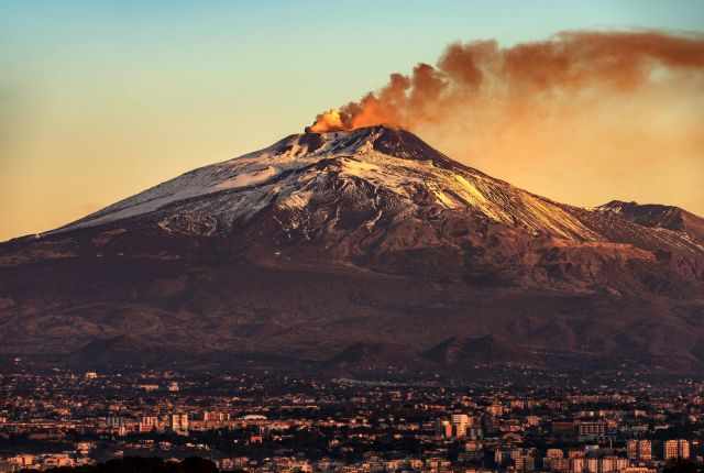 Smoke rising out of the volcano with small snow patches on Etna