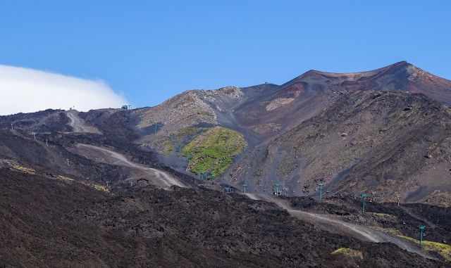 The long cable car on the black lava field on Etna.