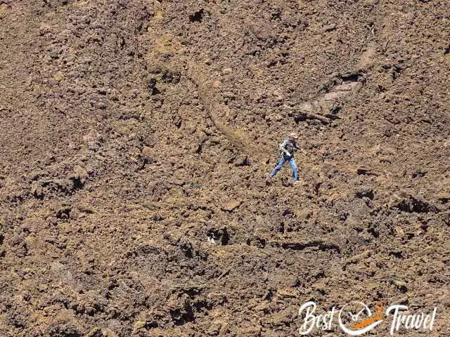 A visitor hiking on a sharp rocky lava field