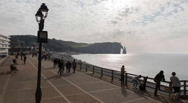 Visitors walking along the promenade in the sun watching the arches