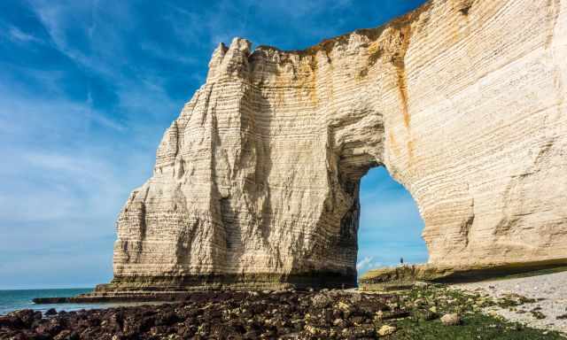 A man standing under the arch at low tide