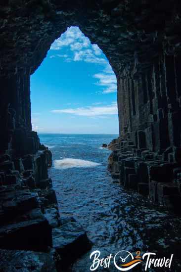 View from inside Fingal’s Cave, with dark basalt columns framing the bright opening toward the sea and sky.
