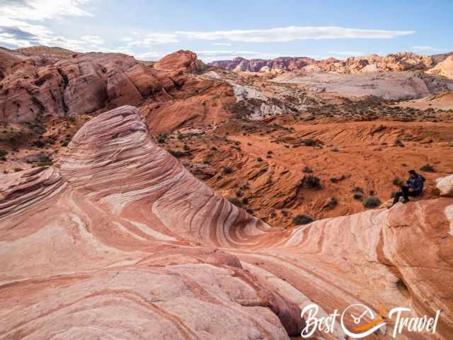 A hiker sittin on the rock formation called Fire Wave