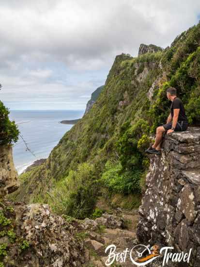 A hiker sitting on a wall and looking to a Faja.