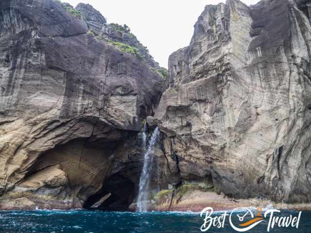 A waterfall and cave in Flores seen from the boat