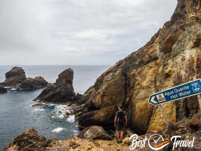 A hikers close to the sea with a trail sign hot water.