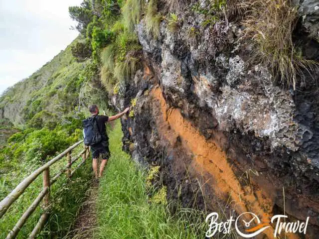 A hiker at a wall with different lava layers.