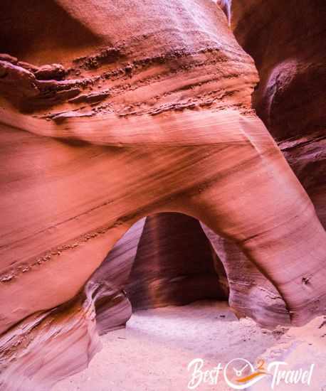 An arch in reddish sandstone in a slot canyon