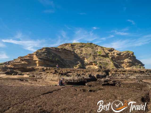 Visitors at tide pools and one man on top of the rock.