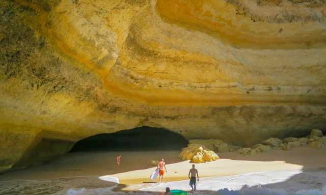 Several swimmers with boards reaching Benagil Cave