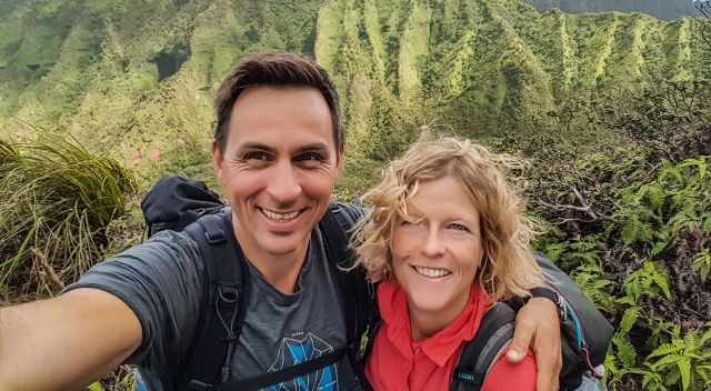 My husband and I on a trail in lush vegetation.