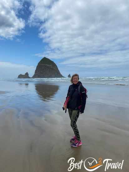 A woman with warm clothes on Cannon Beach and Haystack in the back.