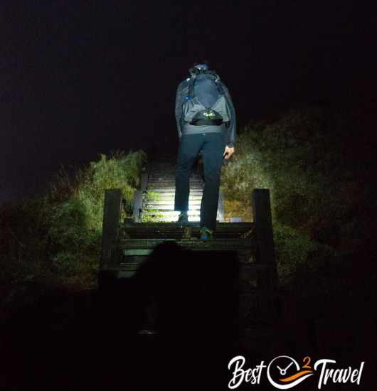 A hiker with a headlamp ascending Hehuan before sunrise