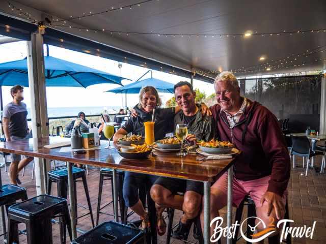 Three adults having dinner in a restaurant with view to the sea