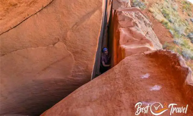 A woman hiker in the narrow crack in the wall