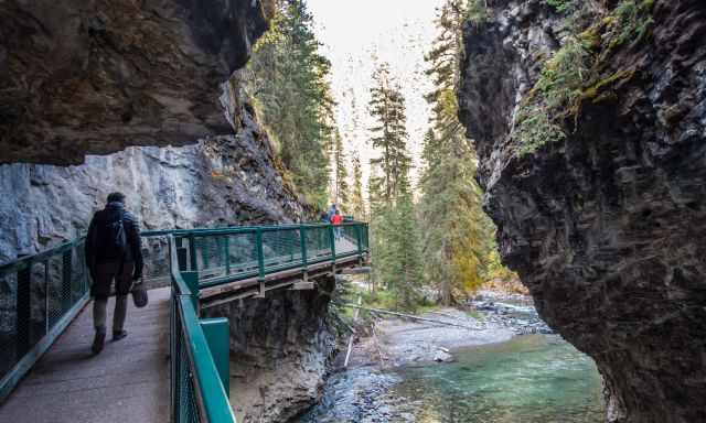 A man walking on the catwalk in Johnston Canyon above Johnston Creek