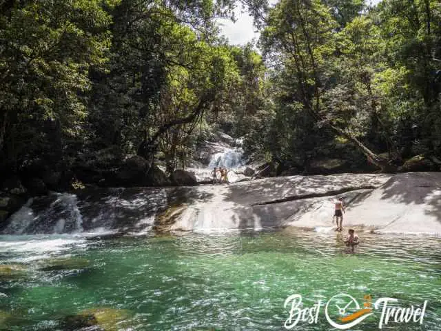 Visitors on a rock and pool at a waterfall.