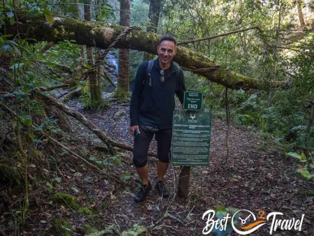 A hiker at the trail sign which indicates the end.