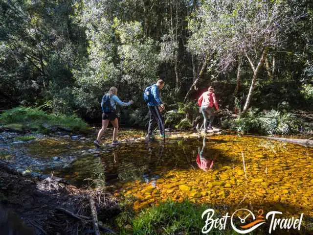 Three hikers crossing the Milwood Creek.