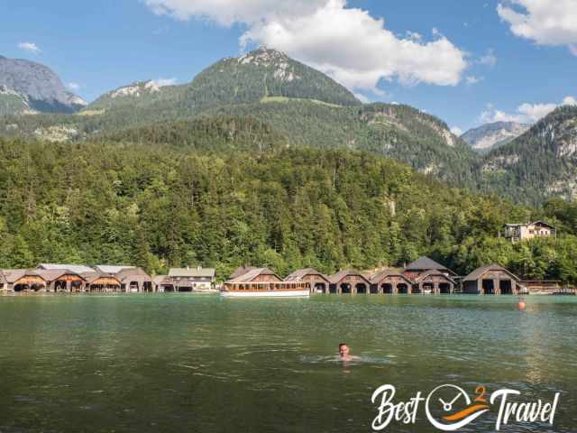 A swimmer in front of the wooden boathouses that house the electric tour boats on Lake Königssee.