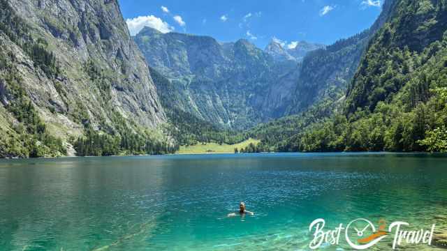 A woman swimming in Oberersee with the Fischunkelalm meadow and steep mountain walls in the background.