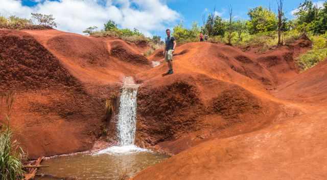 Waimea Canyon waterfall at the beginning trembling down over red clay