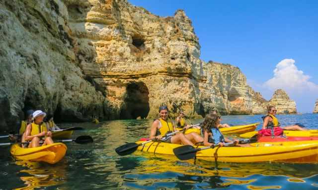 Lots of kayaks on the sea along the rugged coastline.