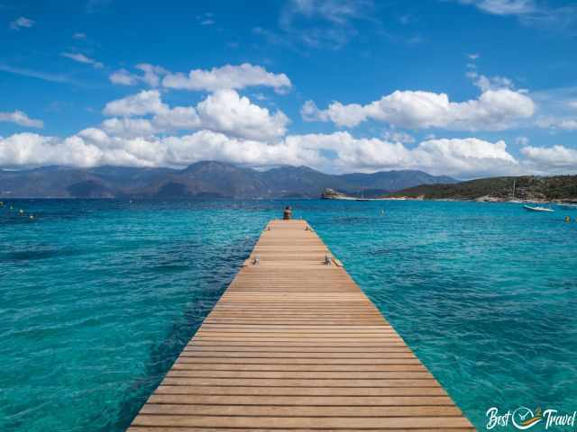 A visitor sits on the jetty and admires the sea.
