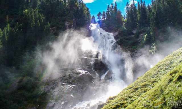 View from the bottom up to the waterfall in summer with much spray