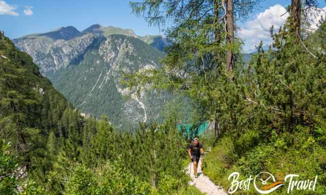 A hiker on trail number one to Seekofel in high elevation with Lago die braies in the back.